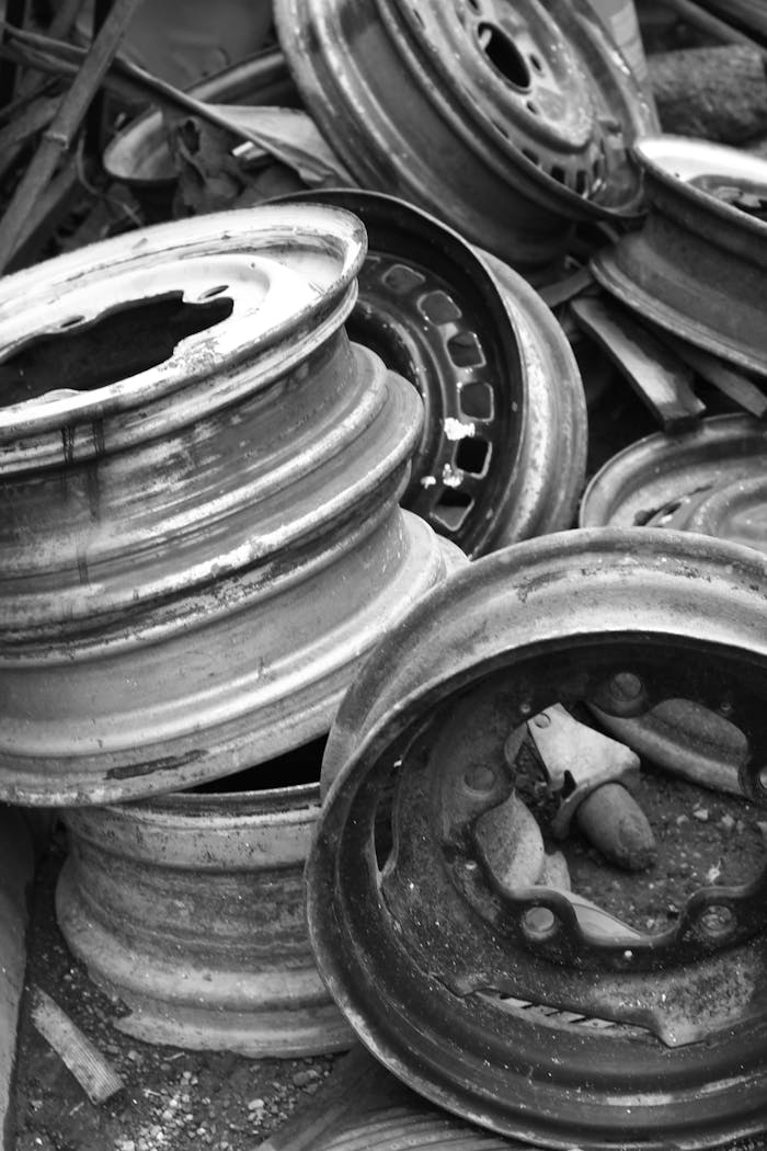 Black and white photo of stacked rusty steel wheels in an industrial setting.